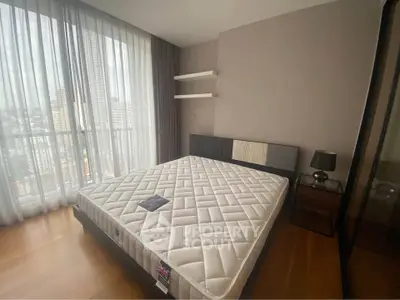 Modern bedroom with large window and city view, featuring a stylish bed and elegant decor.