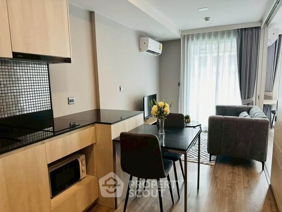 Modern open-plan living room with kitchen, featuring sleek furniture and natural light.