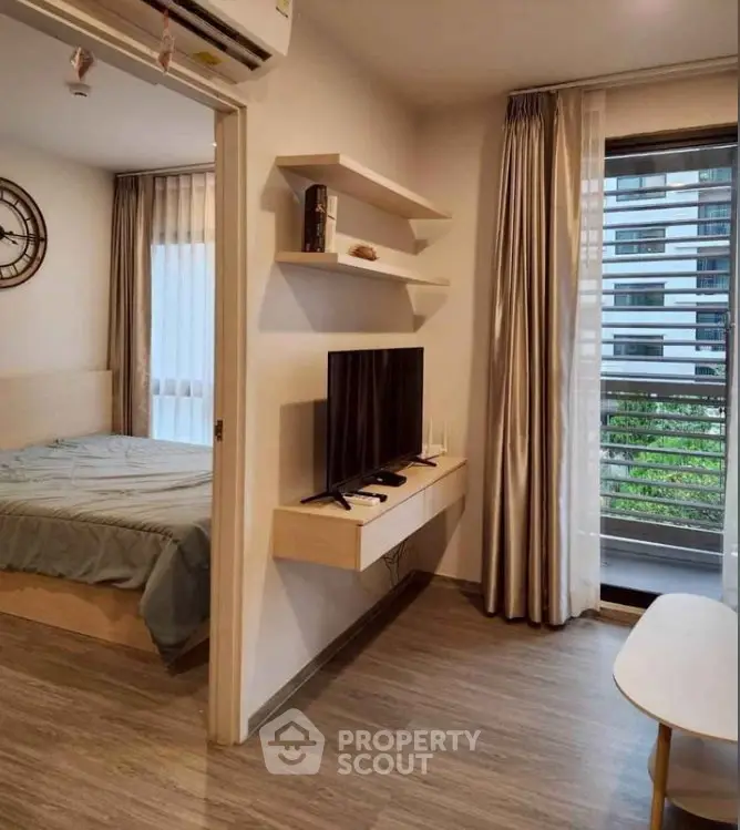 Modern apartment interior with cozy bedroom and stylish living area featuring a wall-mounted TV and large windows.
