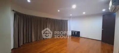 Spacious empty room with wooden flooring and large windows, perfect for customization.