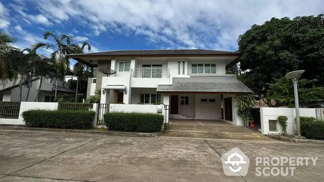 Spacious two-story white house with large driveway and tropical palm trees, offering a serene suburban living experience.