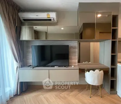 Modern living room with sleek TV unit and stylish chair, featuring elegant wood flooring and large window.