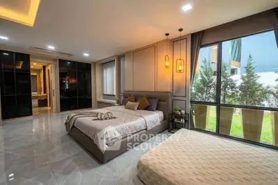 Luxurious bedroom with large windows and modern decor, featuring a spacious layout and garden view.