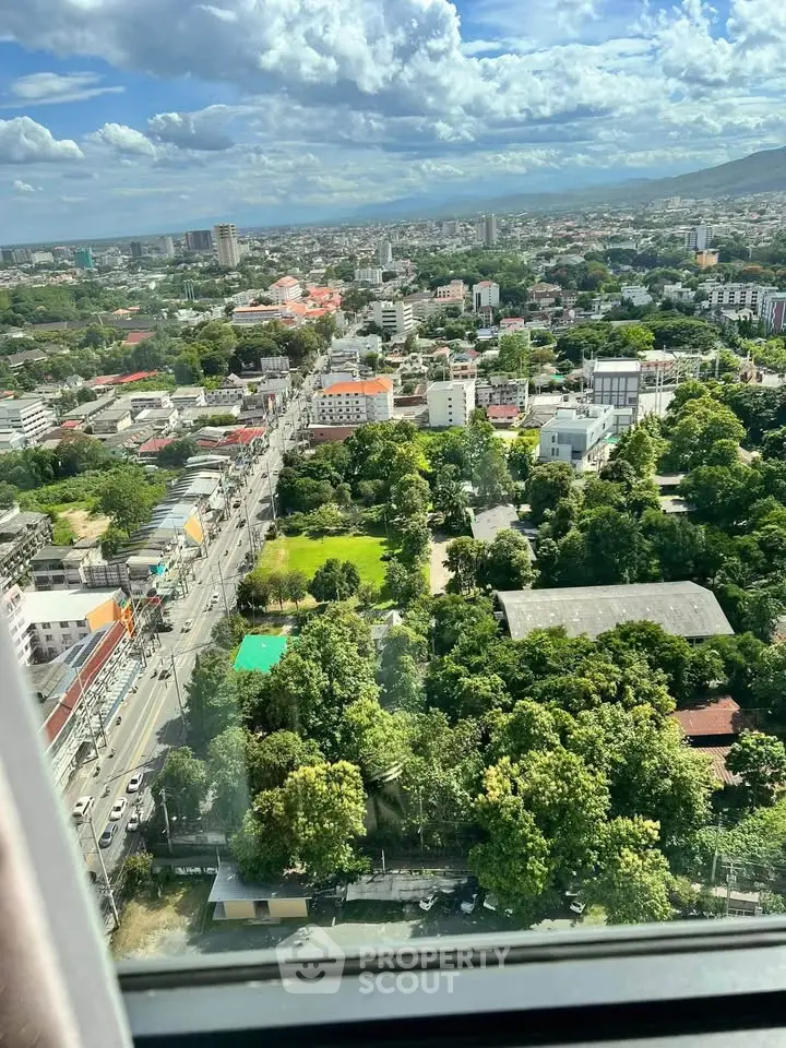 Stunning cityscape view from high-rise window showcasing lush greenery and urban skyline.