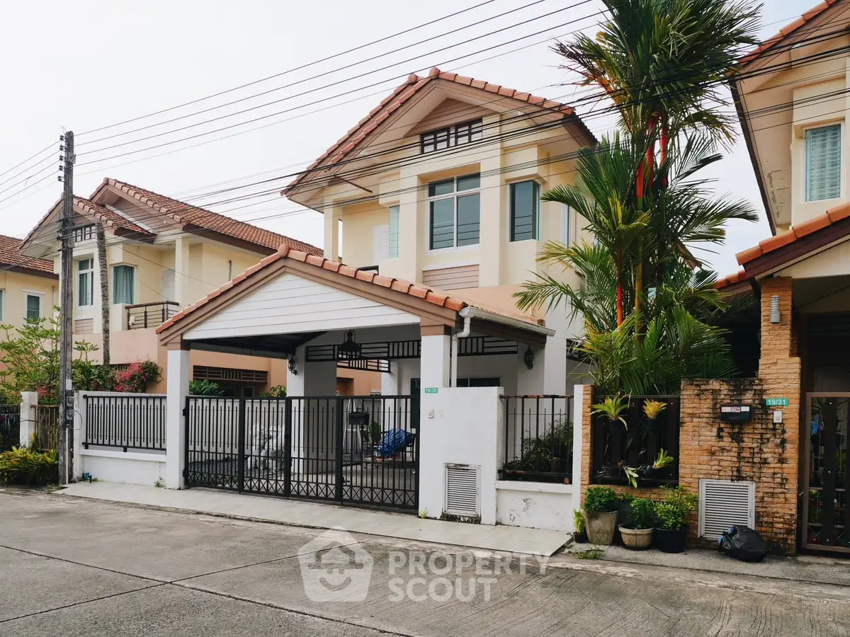 Charming suburban house with tiled roof and gated driveway in a peaceful neighborhood.