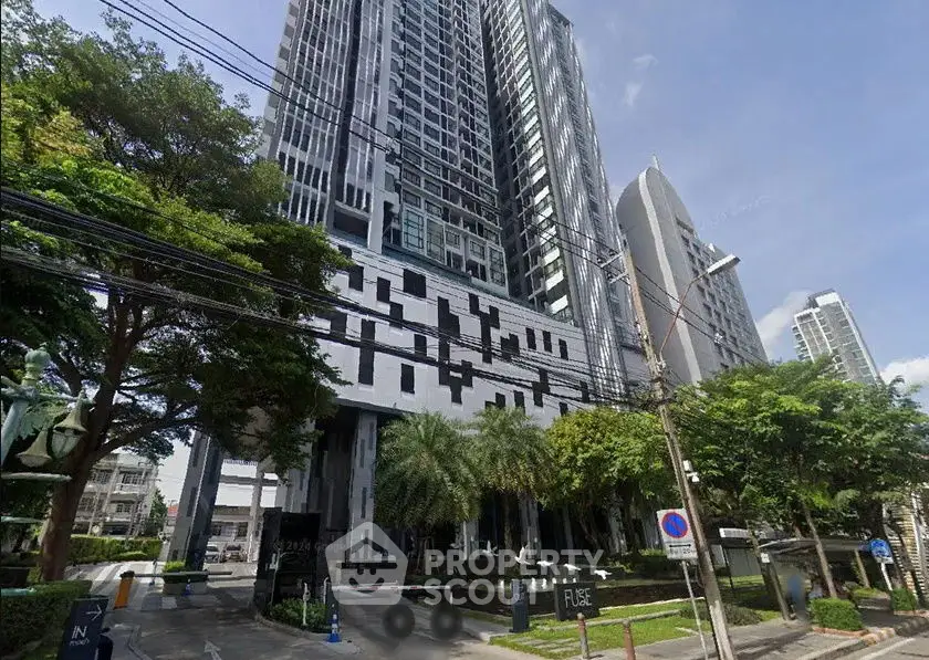 Modern high-rise building with unique facade and lush greenery in urban setting.