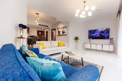 Spacious modern living room with stylish decor and open layout, featuring a blue sofa and elegant lighting.