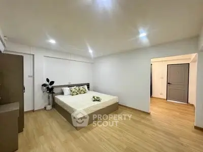 Spacious modern bedroom with wooden flooring and minimalist decor
