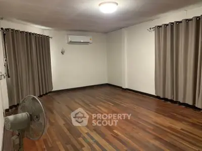 Spacious empty room with wooden flooring and air conditioning, ideal for customization.