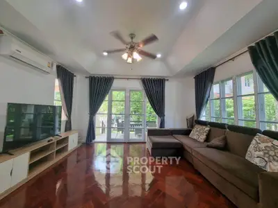 Spacious living room with elegant decor and large windows offering lush garden views.