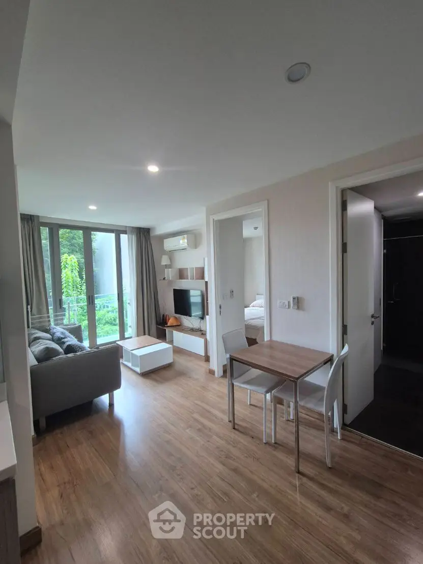 Modern apartment with open living area and balcony view, featuring sleek furniture and natural light.