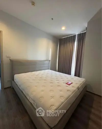 Spacious bedroom with large bed and natural light through curtains.