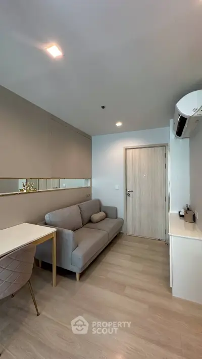 Modern living room with sleek design, featuring a comfortable sofa, stylish desk, and air conditioning unit.