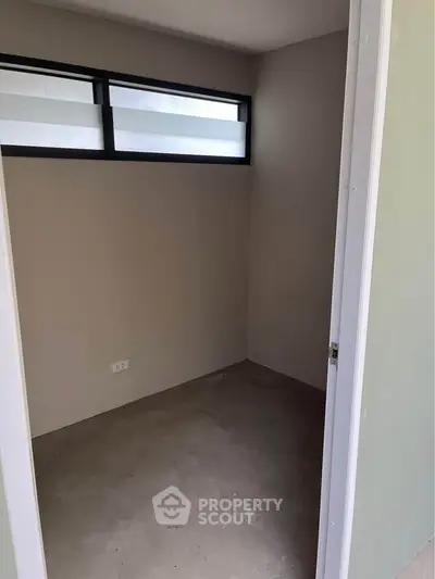 Minimalist small room with high window and neutral walls, perfect for storage or compact office space.