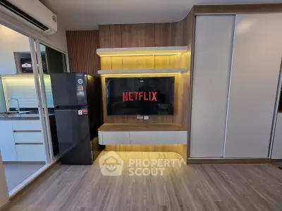 Modern living room with built-in TV unit and adjacent kitchen area, featuring sleek design and wooden flooring.