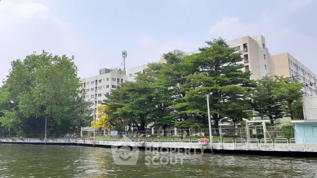 Scenic view of waterfront residential building with lush greenery and serene surroundings.