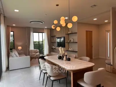 Elegant open-plan living and dining area with modern lighting and stylish decor.