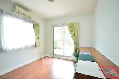 Bright study room with wooden flooring and large window for natural light.