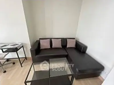Modern living room with sleek black sofa and glass coffee table in a cozy corner setting.