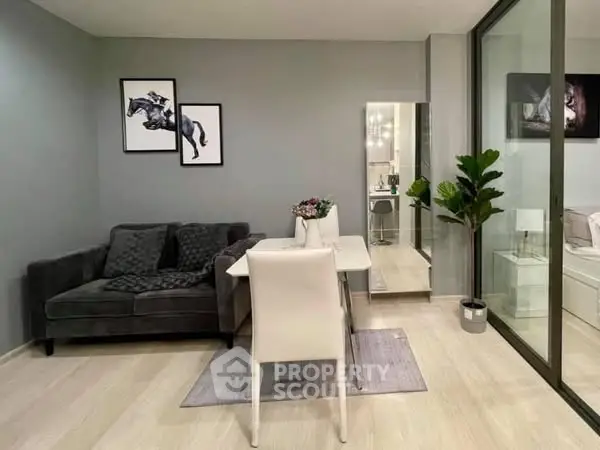 Modern living room with sleek decor and glass partition, featuring cozy seating and stylish artwork.