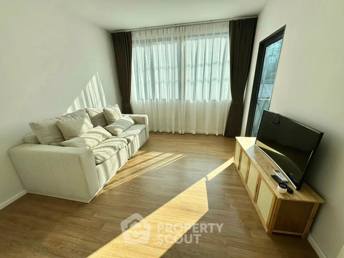 Bright living room with cozy sofa and modern TV setup, perfect for relaxation.