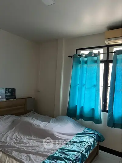 Cozy bedroom with natural light and modern decor, featuring a comfortable bed and vibrant curtains.