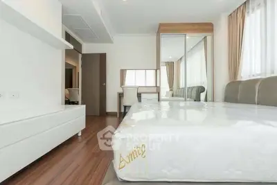 Modern bedroom with hardwood floors and mirrored wardrobe in bright apartment.