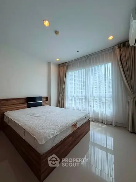 Spacious bedroom with large windows and modern decor in a high-rise apartment.