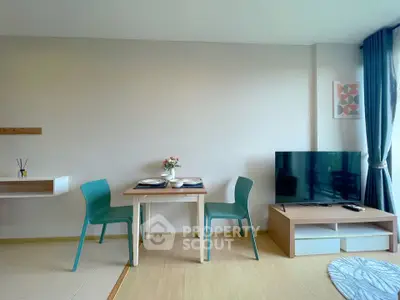 Modern living room with dining area and large TV, featuring stylish decor and natural light.
