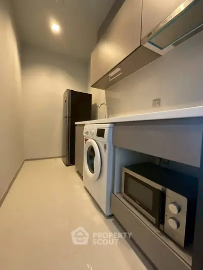 Modern kitchen with sleek appliances including washing machine and microwave, perfect for urban living.