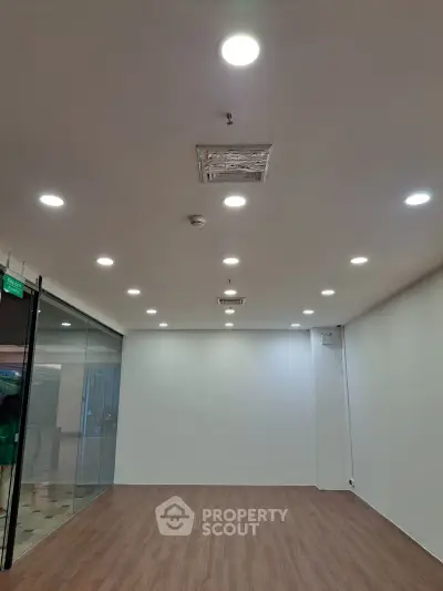 Spacious modern interior with wooden flooring and recessed lighting, ideal for office or retail space.