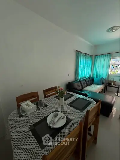 Cozy living room with dining area, featuring a comfortable sofa and elegant table setting, perfect for entertaining.