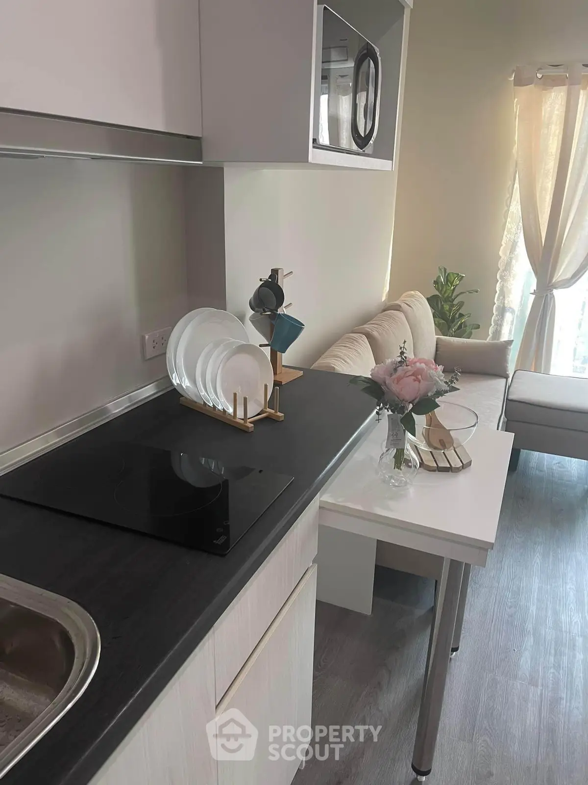 Modern kitchen with sleek design and cozy living area, featuring a built-in microwave and elegant decor.