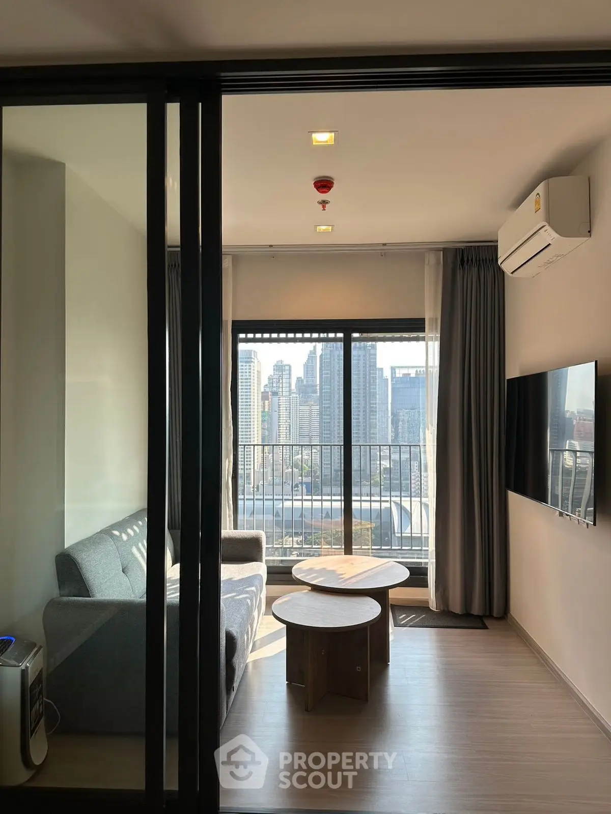 Modern living room with city view, featuring sleek furniture and large windows for natural light.