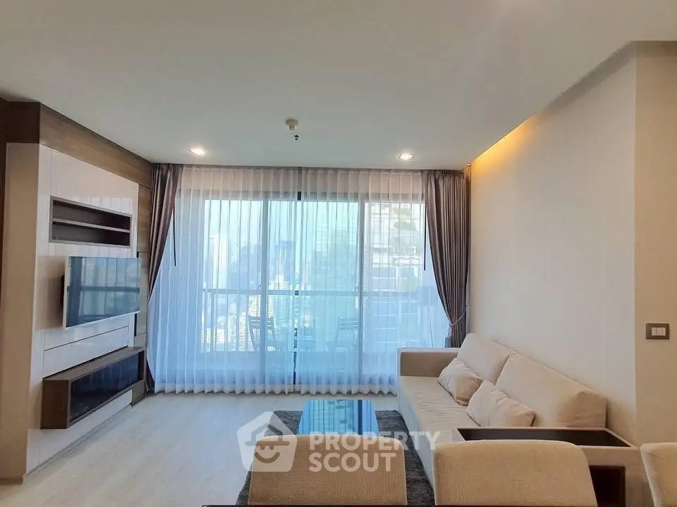 Modern living room with large window and city view, featuring sleek furniture and elegant decor.