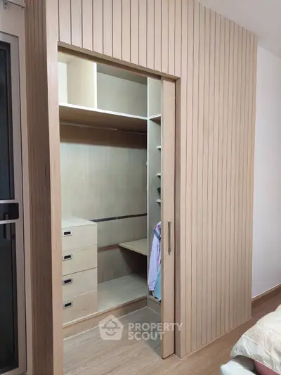 Spacious walk-in closet with wooden paneling and ample storage space in modern bedroom.