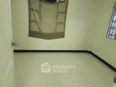 Spacious empty room with tiled floor and window, ideal for customization.