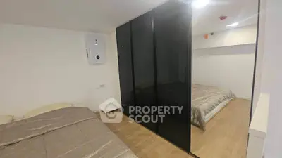 Modern bedroom with sleek black wardrobe and cozy bed in minimalist design.
