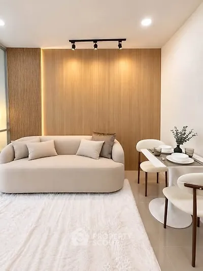 Modern living room with elegant sofa and dining area, featuring stylish lighting and cozy decor.