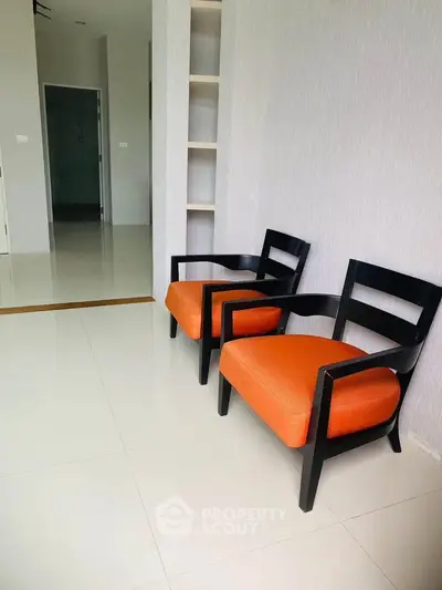 Modern interior with stylish orange chairs and sleek shelving