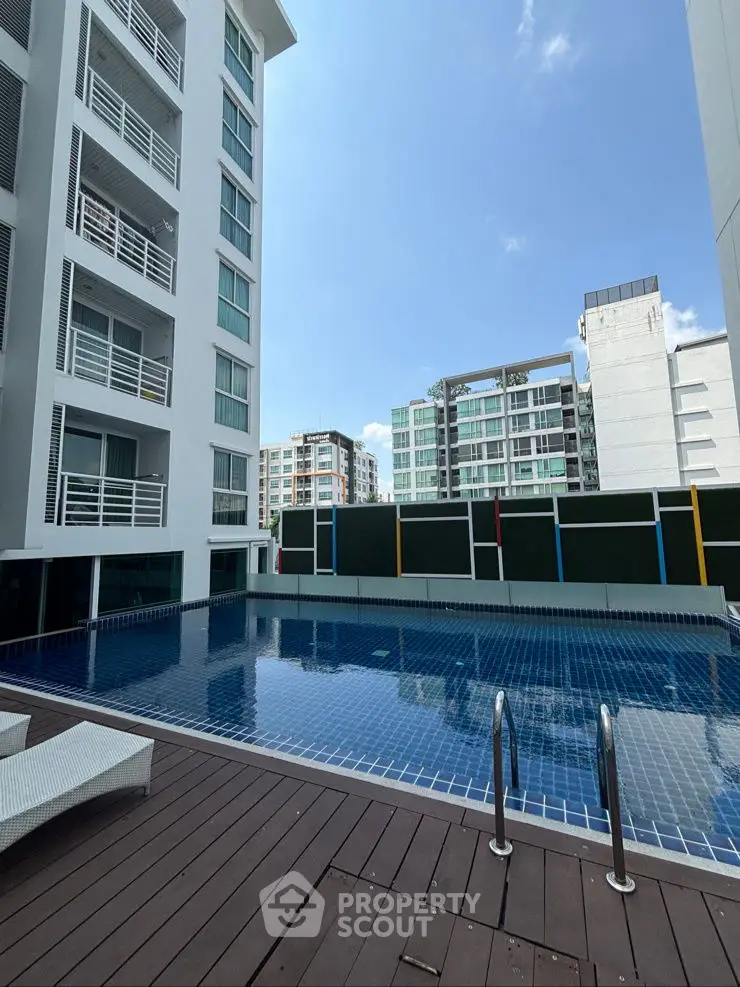 Modern apartment complex with a pristine swimming pool and urban skyline view.