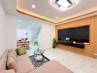 Modern living room with stylish decor and open dining area, featuring elegant lighting and sleek design.