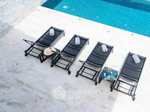 Luxurious poolside area with stylish loungers and refreshing blue water, perfect for relaxation and leisure.