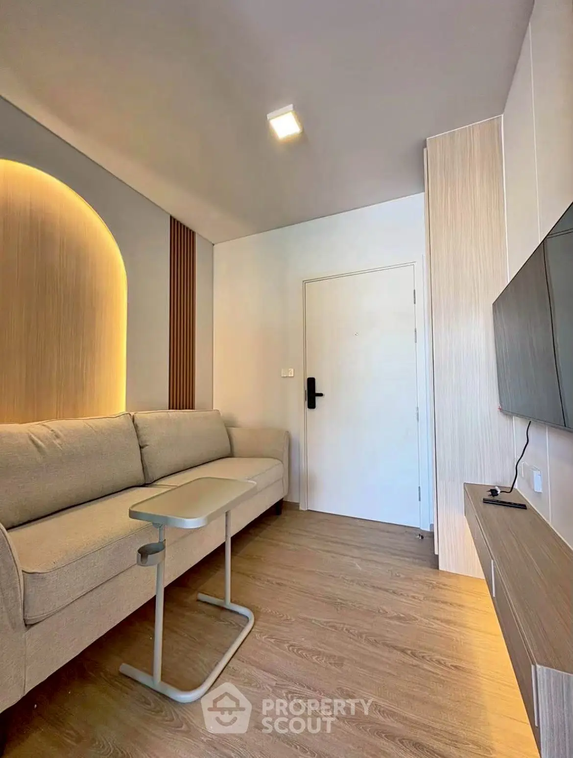 Modern living room with sleek design, featuring a cozy sofa, wall-mounted TV, and stylish lighting.