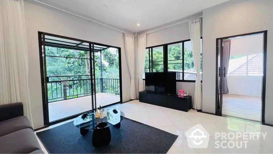 Spacious living room with large windows and balcony access, modern decor and serene view.