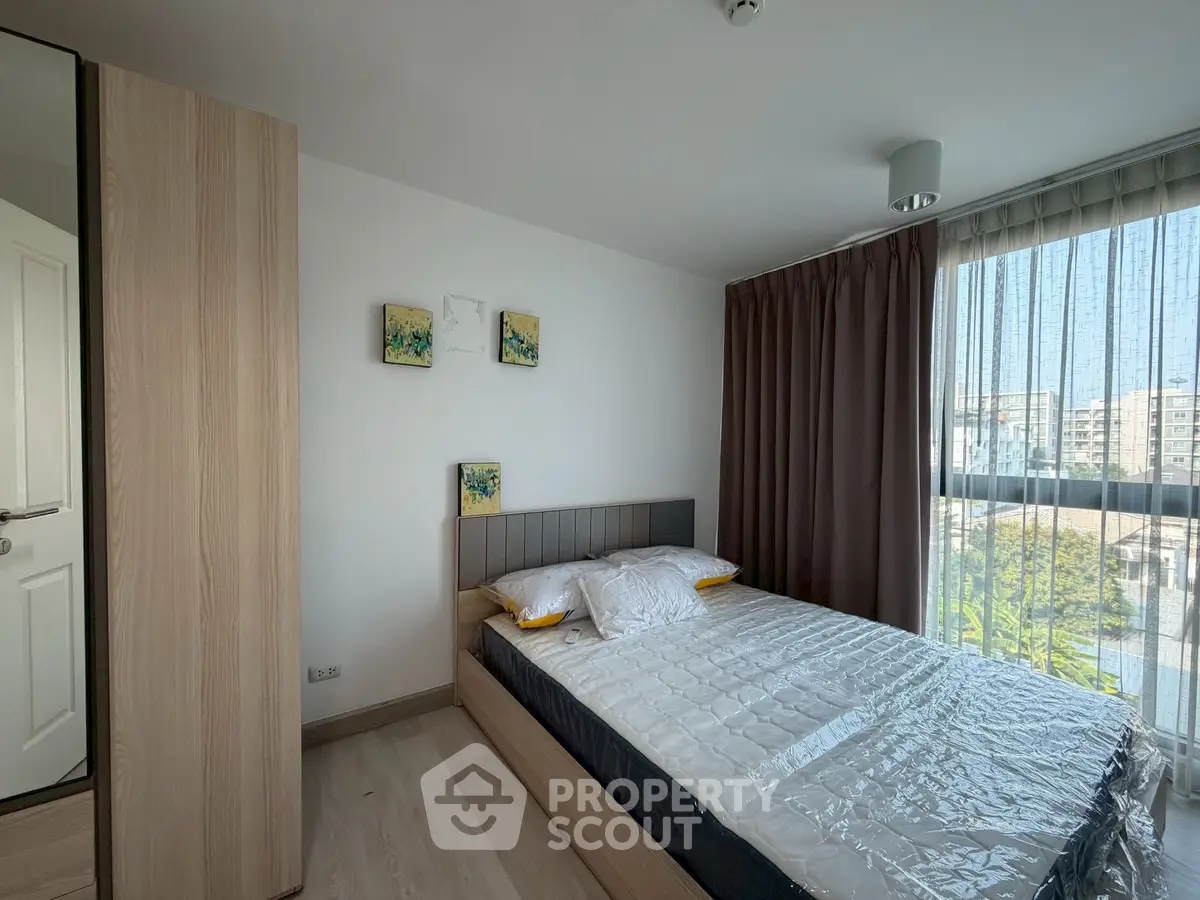Modern bedroom with large window and stylish decor in a contemporary apartment.