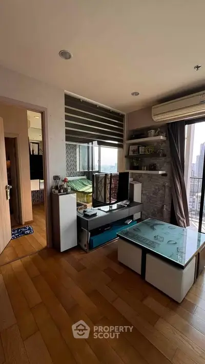 Modern living room with wooden flooring, large window, and stylish furniture in a high-rise apartment.