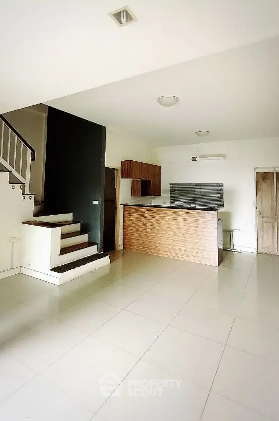Spacious open-plan living area with modern kitchen and staircase