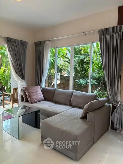 Cozy living room with L-shaped sofa and garden view through large windows.