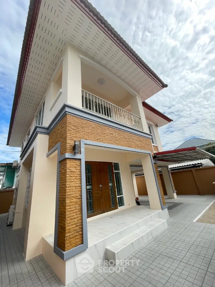 Stunning two-story house with modern design and spacious balcony under a bright blue sky.